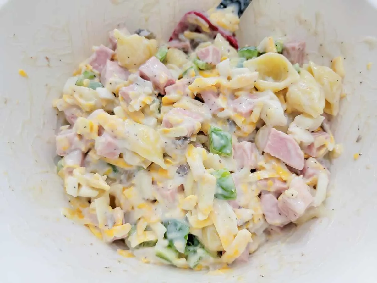 cooked pasta, soup, cheese, milk, onion, green pepper, and black pepper in a large bowl.