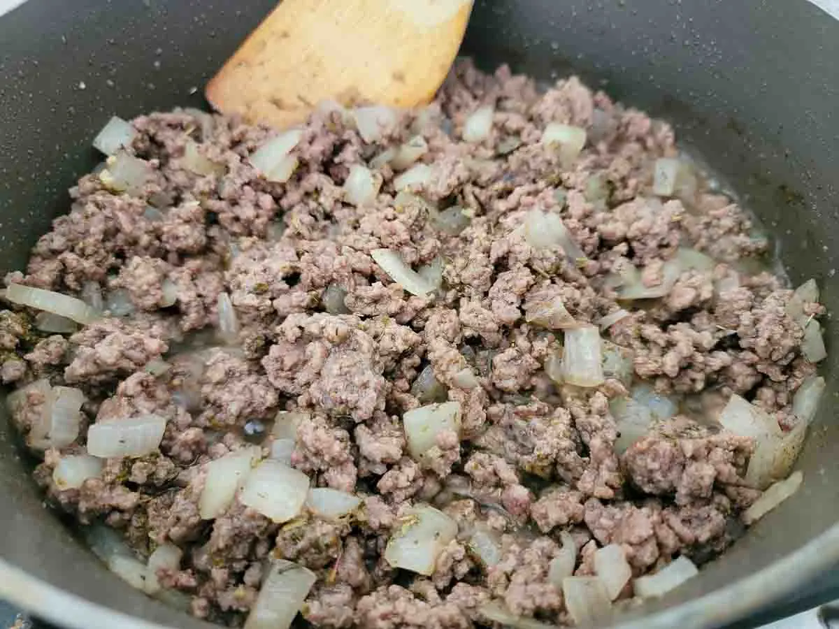 garlic, beef broth, Italian seasoning, ground beef and onions cooking in a pan.