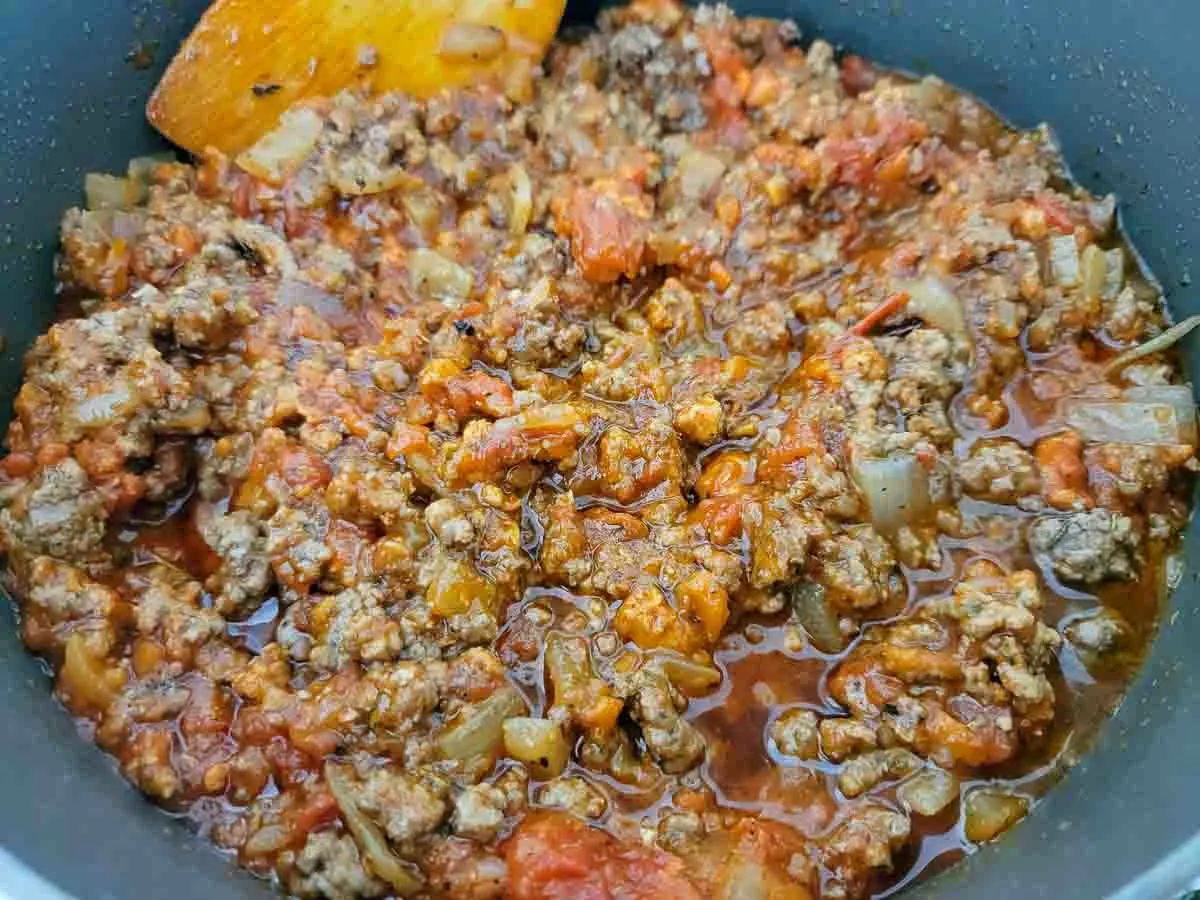 marinara sauce, garlic, beef broth, Italian seasoning, ground beef and onions cooking in a pan.