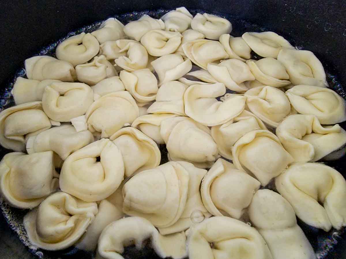 tortellini pasta cooking in a pan of water.