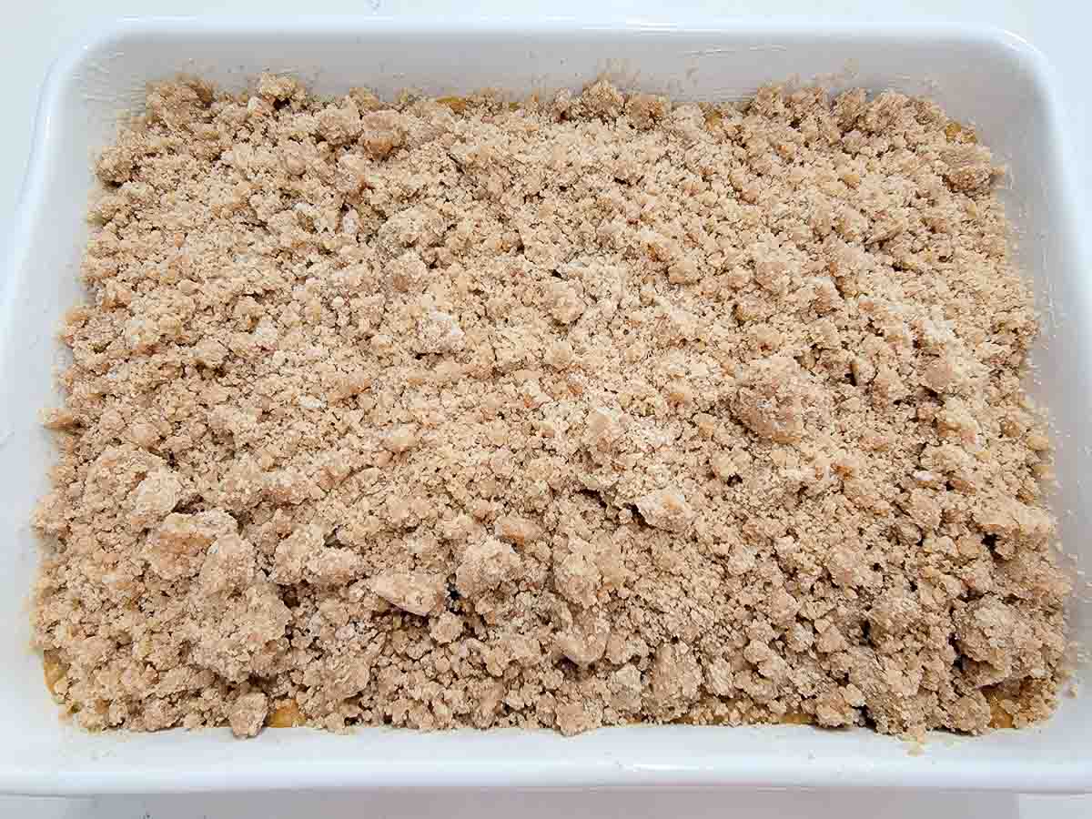 butter, flour, sugar, cinnamon, and salt topping over pumpkin batter in a baking dish.