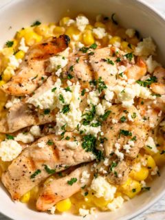 a bowl filled with corn, chicken, cheese, mayo sauce, and seasonings.