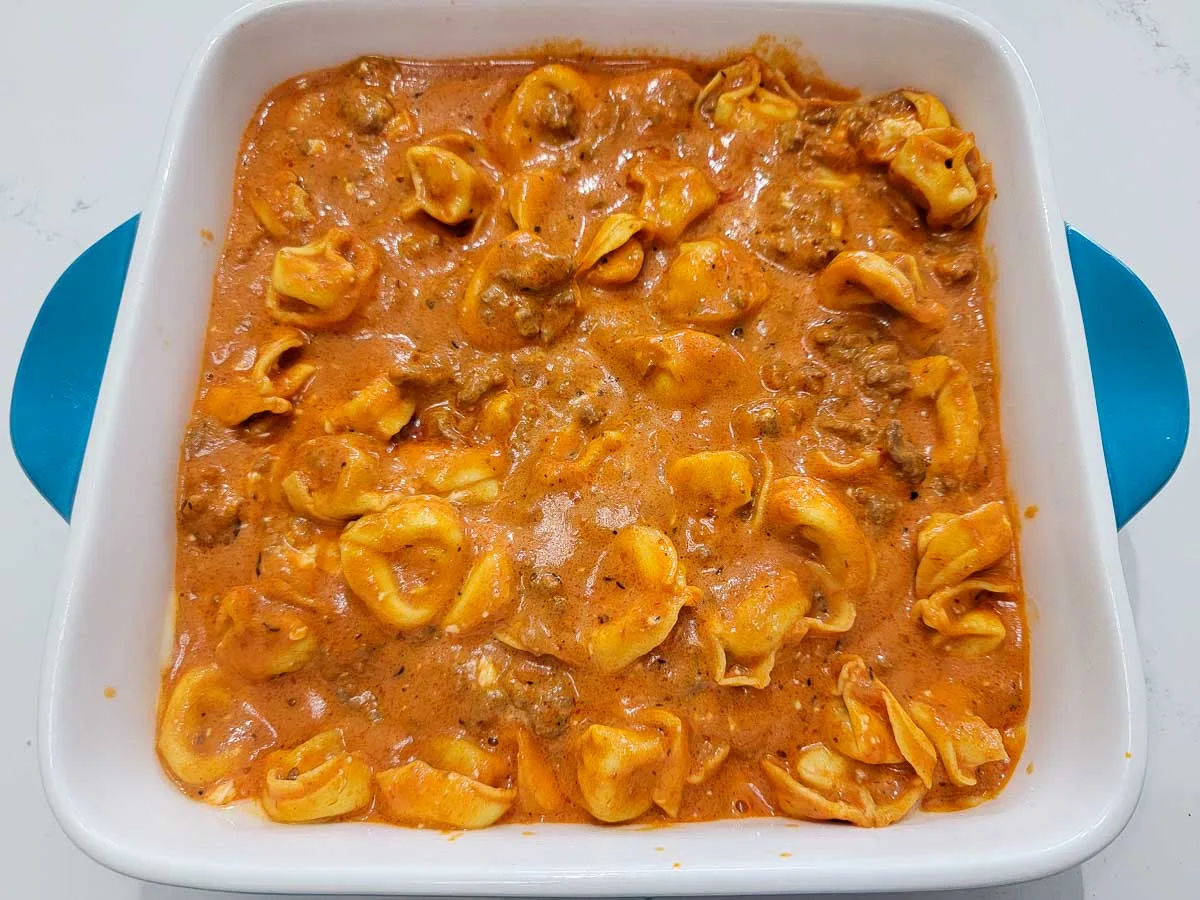 cream cheese, tortellini, marinara sauce, ground beef and seasonings poured into a baking dish.