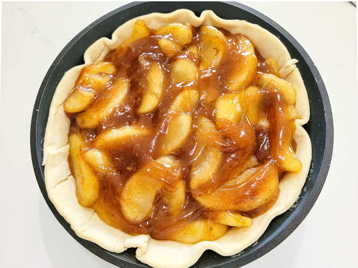 apple pie filling, cinnamon, nutmeg, lemon juice, and lemon zest poured into a raw pie crust.