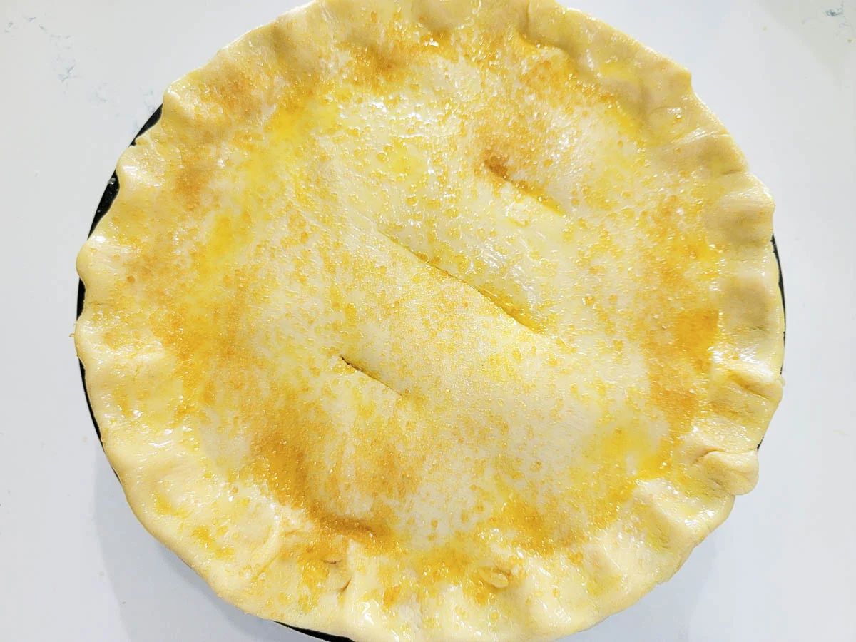 raw pie dough topped with egg wash and turbinado sugar.